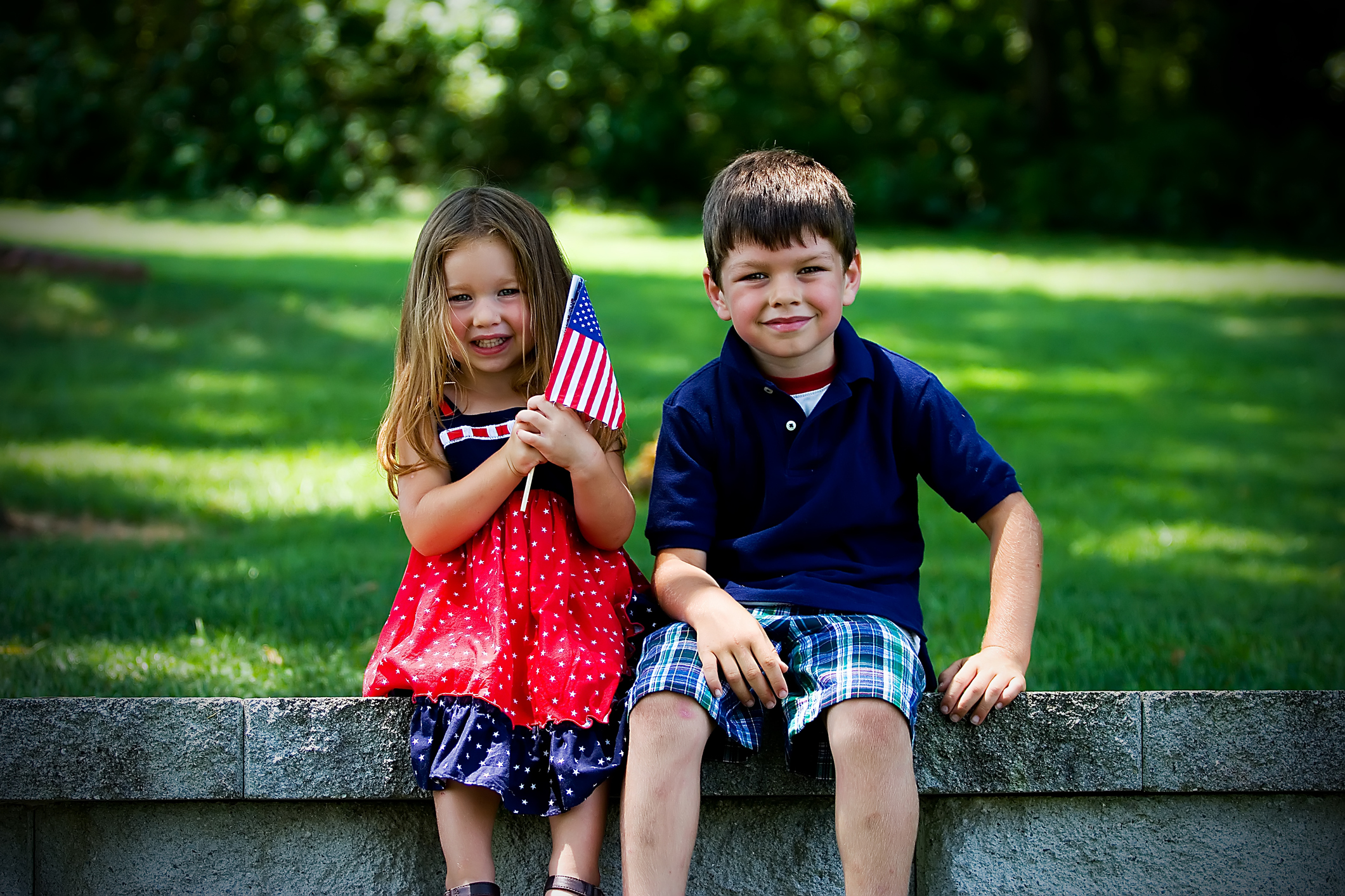 Two kids - Young boy and young girl holding an American flag.