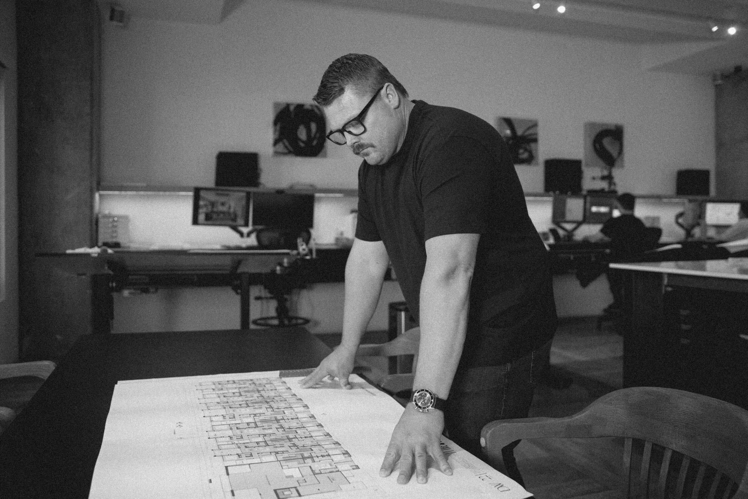 Pario Team Gordon over a desk looking at a blueprint.